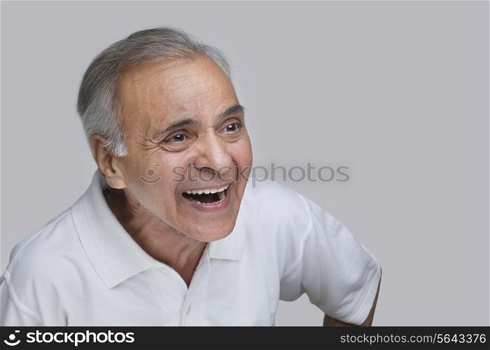 Elderly man laughing over colored background