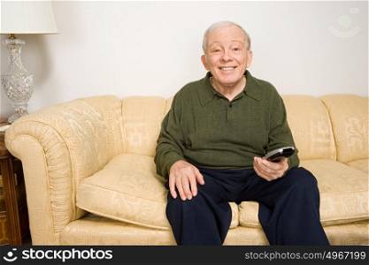 Elderly man on sofa with remote control