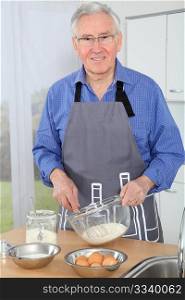 Elderly man preparing cake in home kitchen