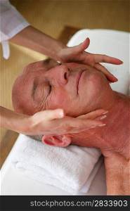 Elderly man receiving a head massage