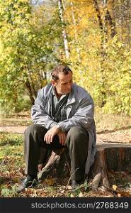 elderly man sits in the park in autumn