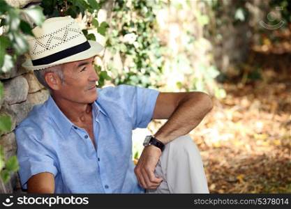 Elderly man sitting against the stone wall