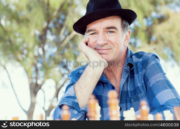 Elderly man sitting outdoors with chess. Thinking chess strategy