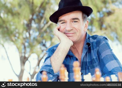 Elderly man sitting outdoors with chess. Thinking chess strategy