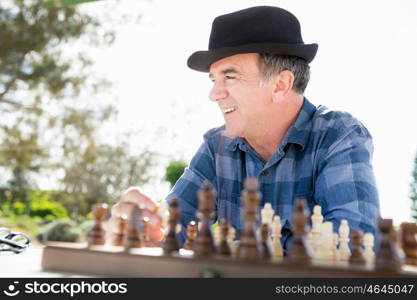 Elderly man sitting outdoors with chess. Thinking chess strategy