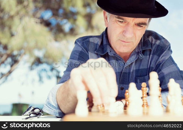 Elderly man sitting outdoors with chess. Thinking chess strategy