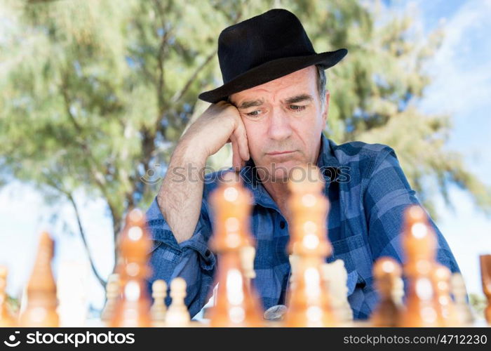 Elderly man sitting outdoors with chess. Thinking chess strategy