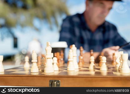 Elderly man sitting outdoors with chess. Thinking chess strategy