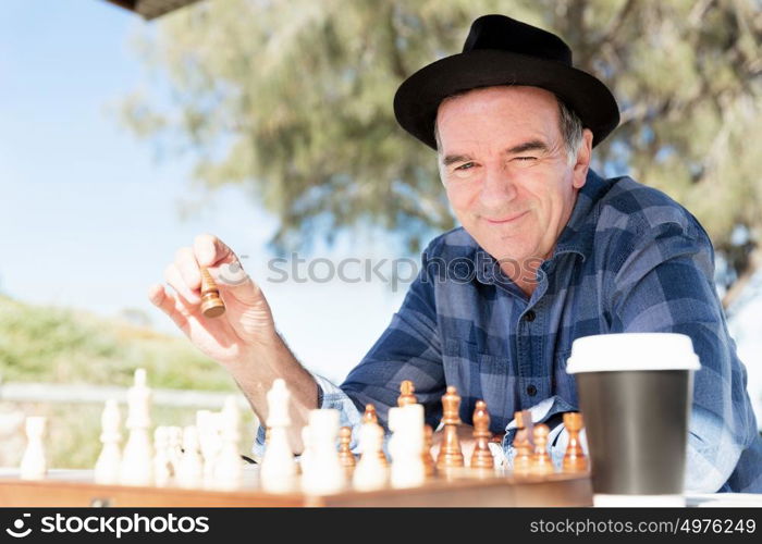 Elderly man sitting outdoors with chess. Thinking chess strategy