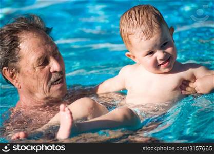 Elderly man swimming with a baby