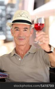 Elderly man toasting with glass of rose wine