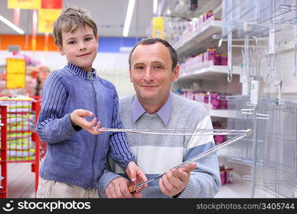 elderly man with boy in store with grill for roasting in hands, loking at camera