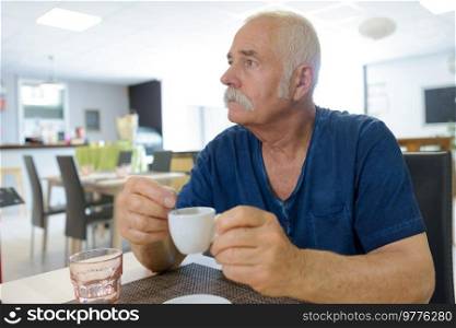 elderly man with cup of coffee at summer cafe