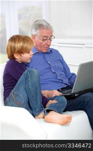 Elderly man with grandkid using laptop computer