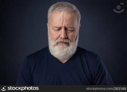Elderly man with gray beard looking down and thinking