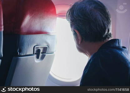 elderly old elder senior woman looking through airplane aircraft window