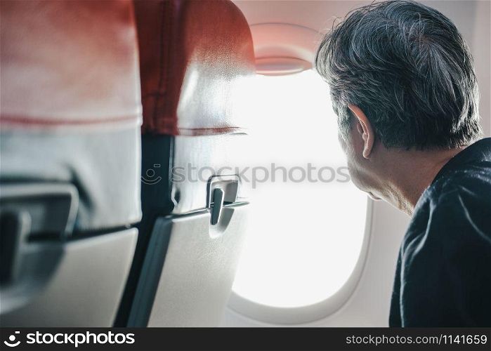elderly old elder senior woman looking through airplane aircraft window