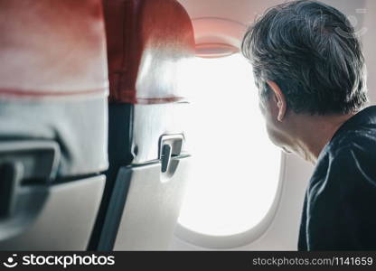 elderly old elder senior woman looking through airplane aircraft window