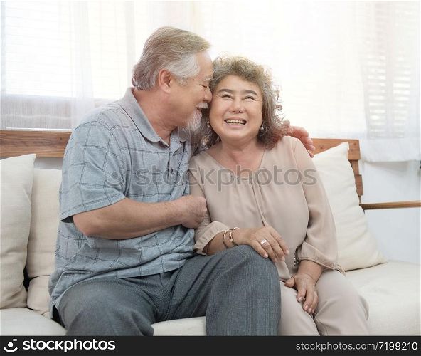 Elderly senior asian couple happy together at home.Grandfather and grandmother sit on coach in living room at home have leisure time in retirement lifestyles.
