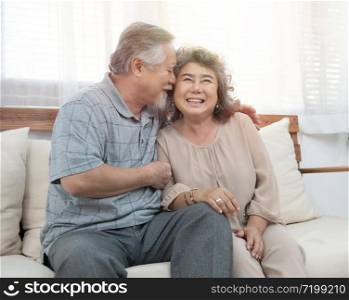 Elderly senior asian couple happy together at home.Grandfather and grandmother sit on coach in living room at home have leisure time in retirement lifestyles.