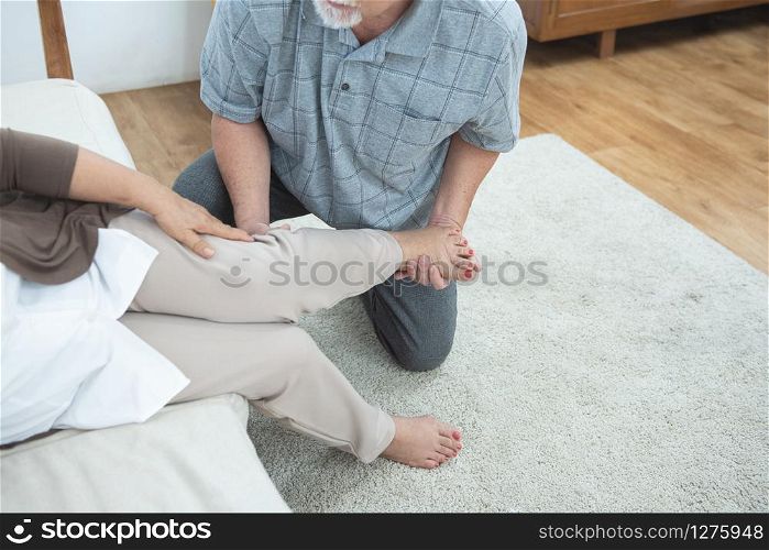 Elderly senior old grandmother fall down leg and ankle pain hurt,sit on couch with hand of grandfather support with treatment therapy at home.