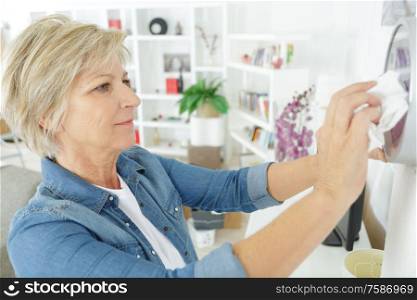 elderly senior woman cleaning clock