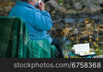 elderly woman drinking coffee from a cup at Autumn park, Side View