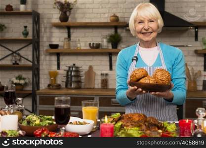 elderly woman holding plate with bread looking camera