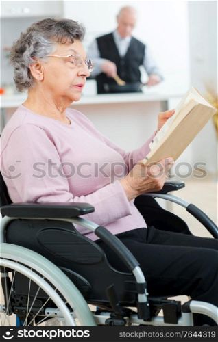 elderly woman on the wheelchair reading a book