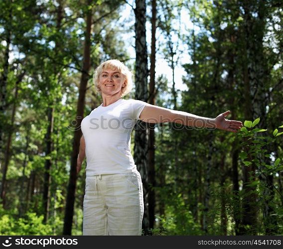 Elderly woman playing sports in the forest.