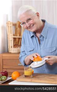 Elderly woman pouring freshly squeezed orange juice