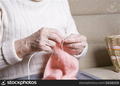 Elderly woman sits knitting