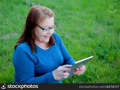 Elderly woman using a tablet while relaxing in the garden