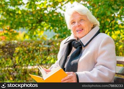 elderly woman with a book resting on a bench