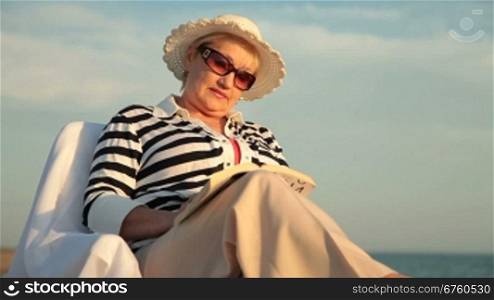 Elderly woman with book at the seaside