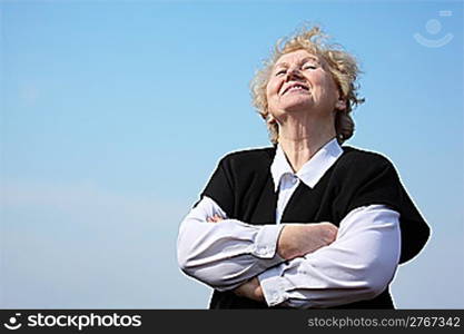 Elderly woman with crossed hands on sky