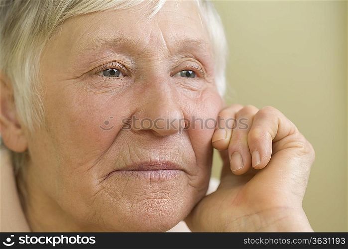 Elderly woman with short grey hair leaning on hand