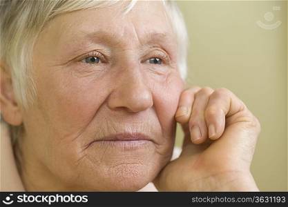 Elderly woman with short grey hair leaning on hand