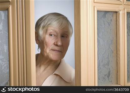 Elderly woman with short grey hair opening front door