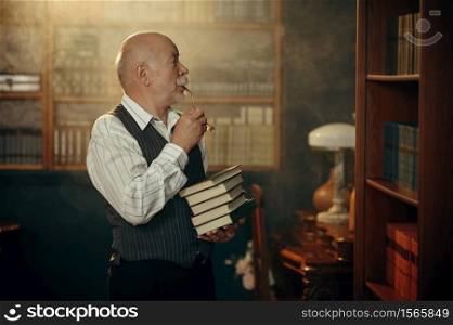 Elderly writer holds stack of books in home office. Old man in glasses writes literature novel in room with smoke, inspiration. Elderly writer holds stack of books in home office
