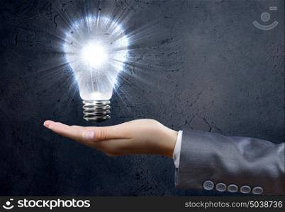 Electric bulb. Close up of businesswoman hand holding bulb in palm