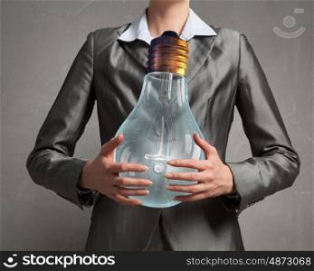 Electric bulb in woman hand. Close up of businesswoman holding glass glowing light bulb in hands