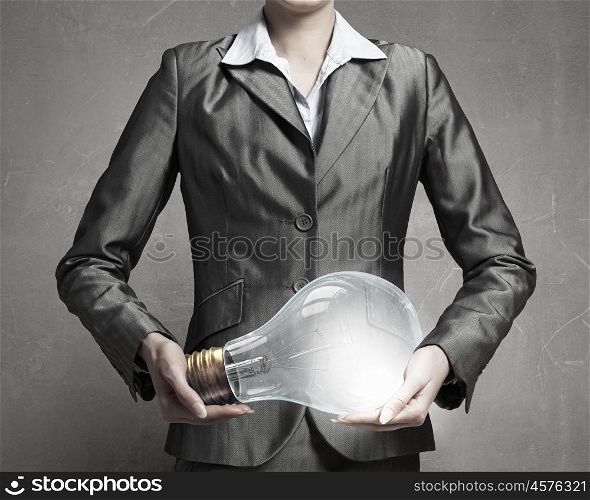 Electric bulb in woman hand. Close view of businesswoman holding in hands glass glowing bulb