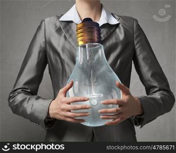 Electric bulb in woman hand. Close view of businesswoman holding in hands glass glowing bulb