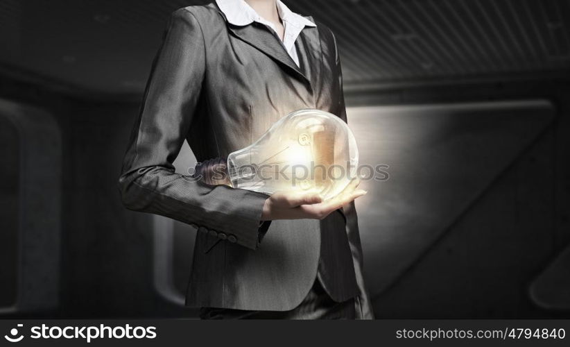 Electric bulb in woman hand. Close view of businesswoman holding in hands glass glowing bulb