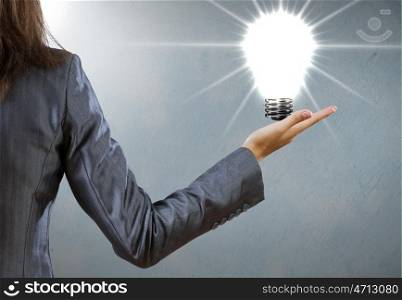 Electric bulb. Rear view of businesswoman holding bulb in palm