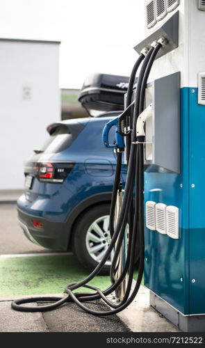 Electric car on gas station. Blue car and electric plug for charging. Ecology green fuels concept.