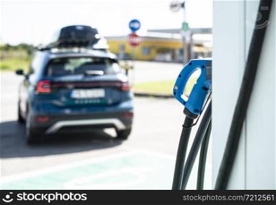 Electric car on gas station. Blue car and electric plug for charging. Ecology green fuels concept.