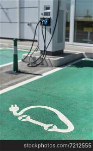 Electric charge station. Electric plug for charging cars. Car charging symbol painted on asphalt. Ecology fuell concept.