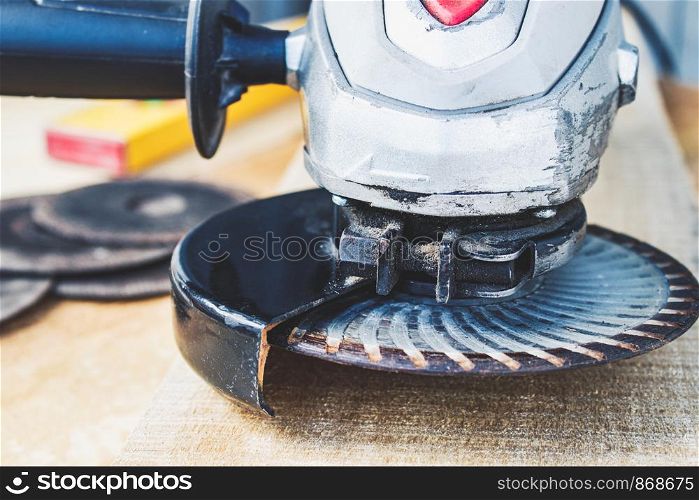 Electric cutting and grinding machine. Angle grinder with abrasive disc on wooden boards. The concept of tools and repair work.. Electric cutting and grinding machine. Angle grinder with abrasive disc on wooden boards.